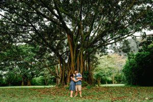 family holding baby in front of banyan tree