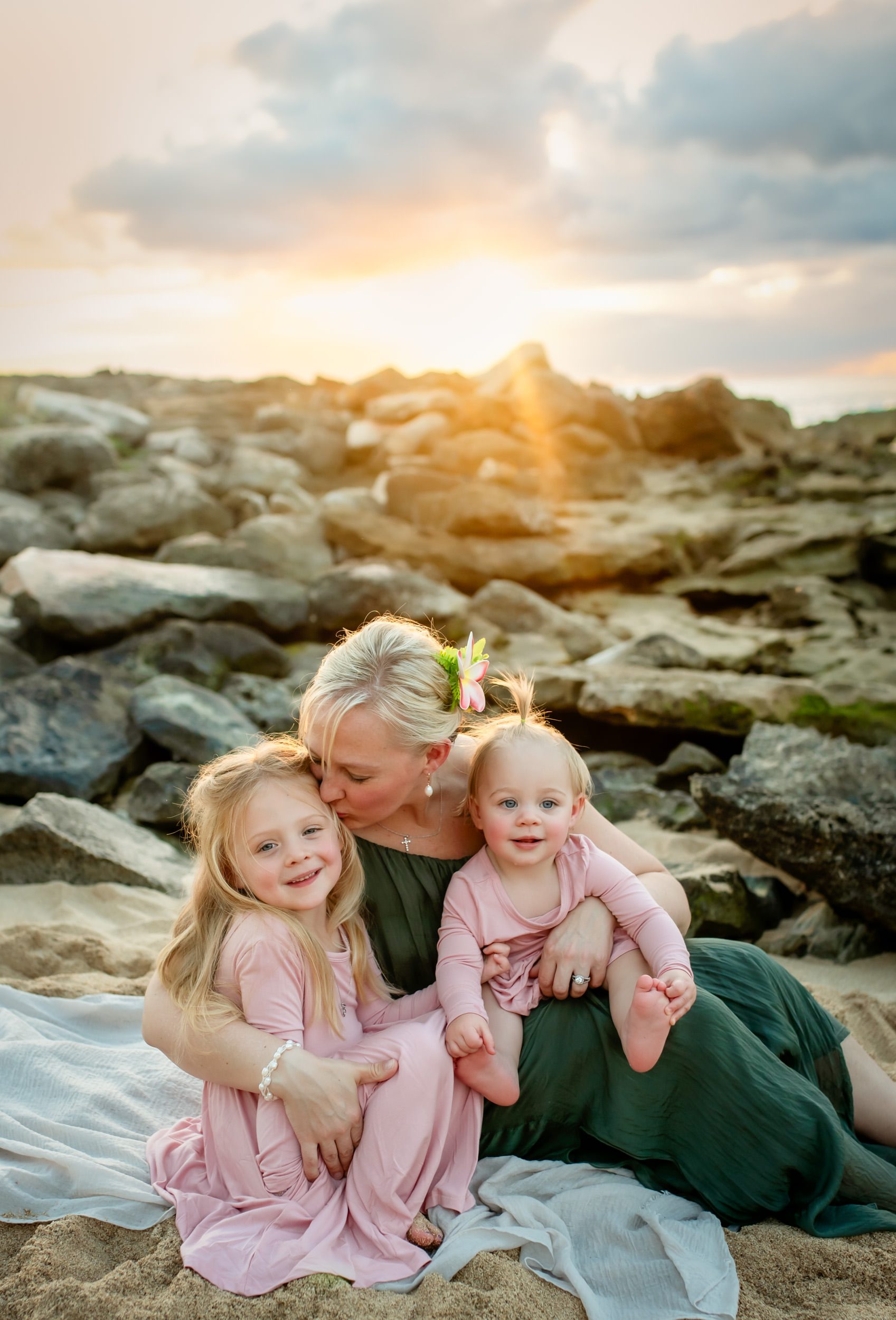 mom kissing daughter at sunset on the beach