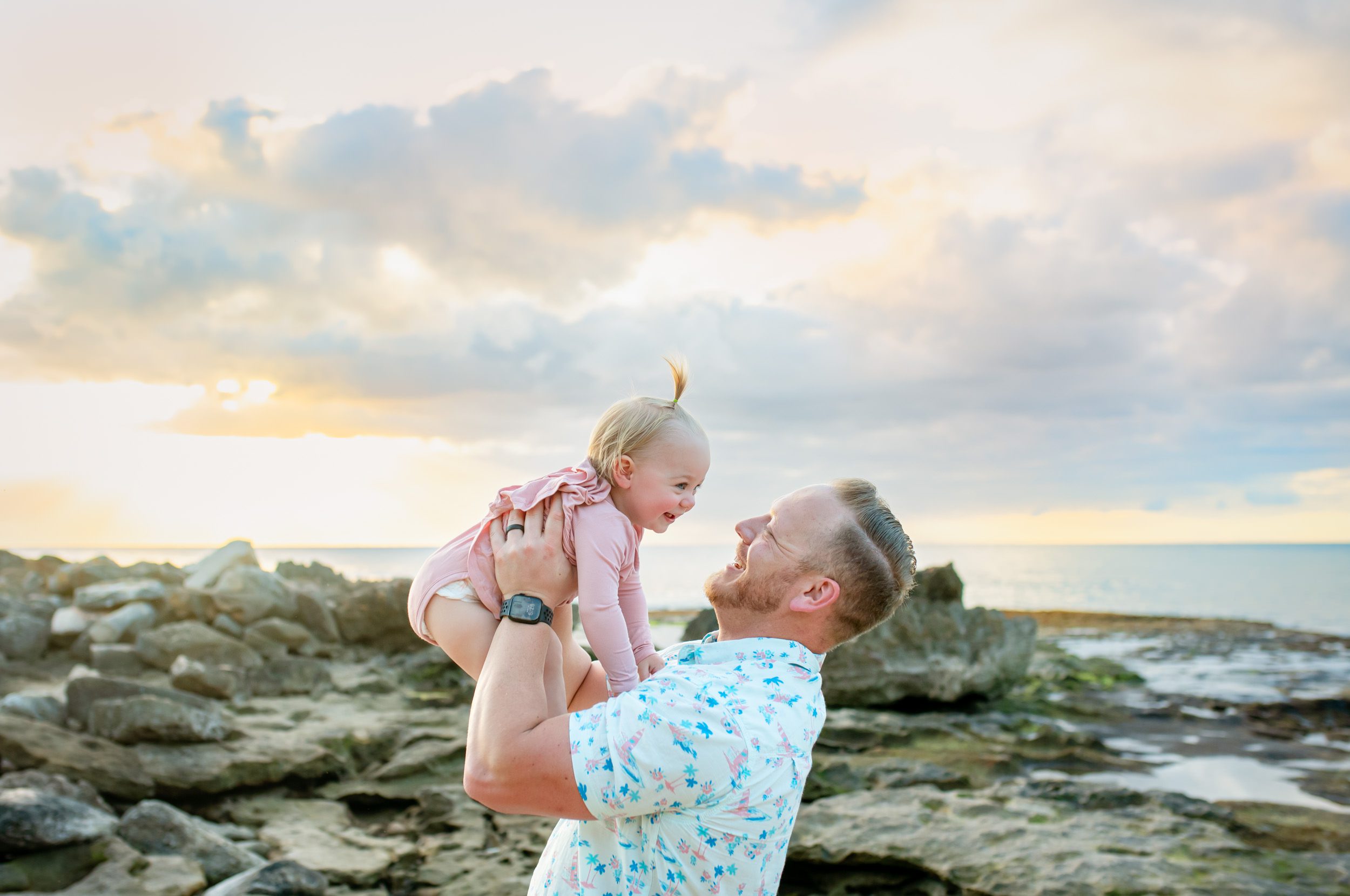Dad and baby playing at the beach at sunset
