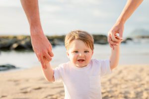 mom and dad holding baby's hands